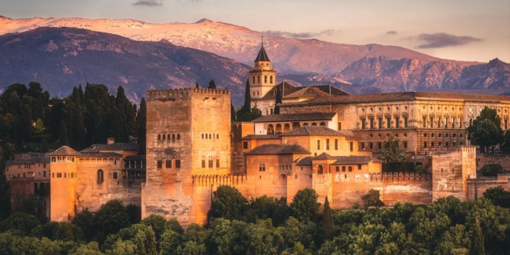 Panoramic view of the ancient Alhambra palace fortress at sunset in Granada, Spain; the historic backdrop for the Echoes & Elements 2026 luxury women’s wellness retreat hosted by 24-year resident Carmen Rivero
