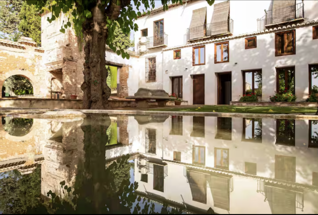 A reflective stone pond in front of the historic northern facade of a 16th-century Spanish Casería; a sanctuary for meditation and stillness during the Echoes & Elements wellness retreat in Granada